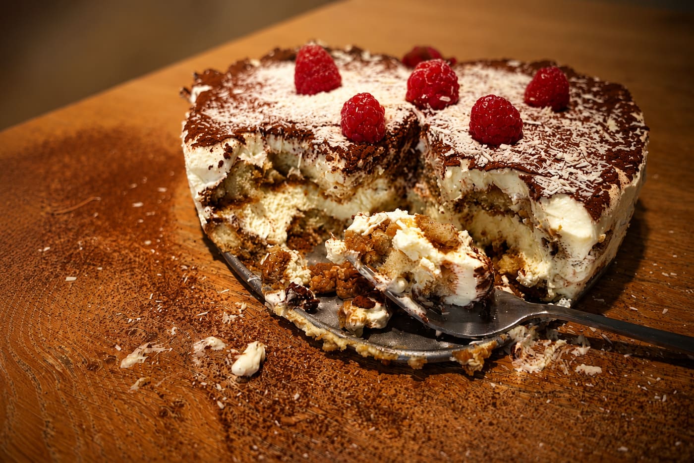 A spoon dug into a heart-shaped tiramisu, the mascarpone giving way in close-up